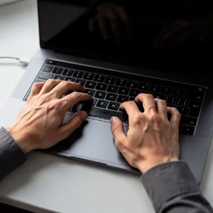 A person typing on a laptop keyboard, showing both hands on the keys. - Black Forest Labs FLUX.2 Max