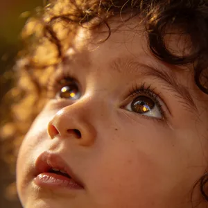 A hyper-realistic photo of a toddler with curly hair and big eyes, looking upward. - Bytedance Seedream 4.5