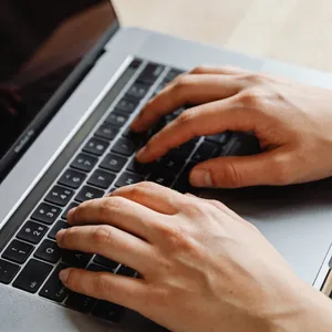 A person typing on a laptop keyboard, showing both hands on the keys. - Bytedance Seedream 4.5