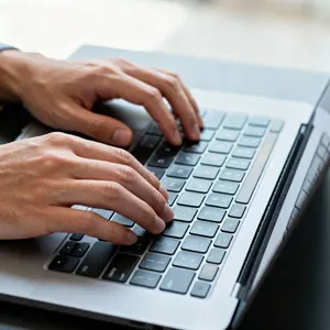 A person typing on a laptop keyboard, showing both hands on the keys. - Bytedance Seedream 4.0
