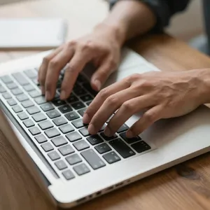 A person typing on a laptop keyboard, showing both hands on the keys. - Alibaba Z-Image Turbo