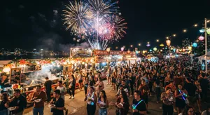 A nighttime festival with fireworks in the sky, food stalls lined up, and crowds mingling. - Google Nano Banana 2 Lite