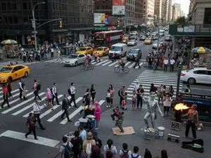A busy city intersection with cars, pedestrians, and street performers all in one frame. - XAI Grok Imagine (Quality)